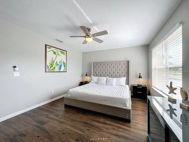 bedroom featuring visible vents, a textured ceiling, wood finished floors, baseboards, and ceiling fan