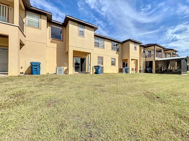 rear view of property featuring a lawn and stucco siding