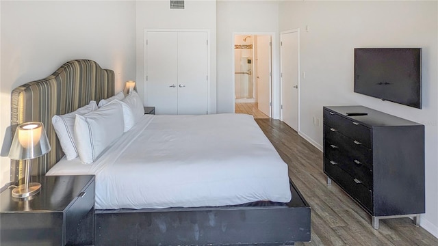 bedroom featuring connected bathroom, baseboards, visible vents, and wood finished floors