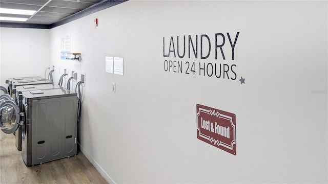 clothes washing area with laundry area, wood finished floors, baseboards, and washing machine and clothes dryer