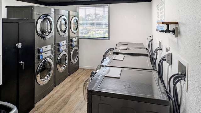 community laundry room with stacked washer / dryer, light wood-type flooring, and baseboards