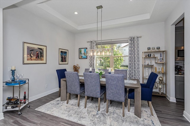 dining area featuring a notable chandelier, dark hardwood / wood-style flooring, and a tray ceiling