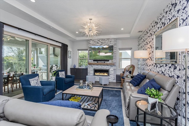 living room with hardwood / wood-style flooring, a large fireplace, a chandelier, and a tray ceiling