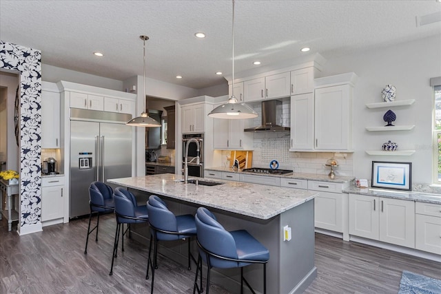 kitchen featuring pendant lighting, white cabinetry, stainless steel appliances, and wall chimney range hood