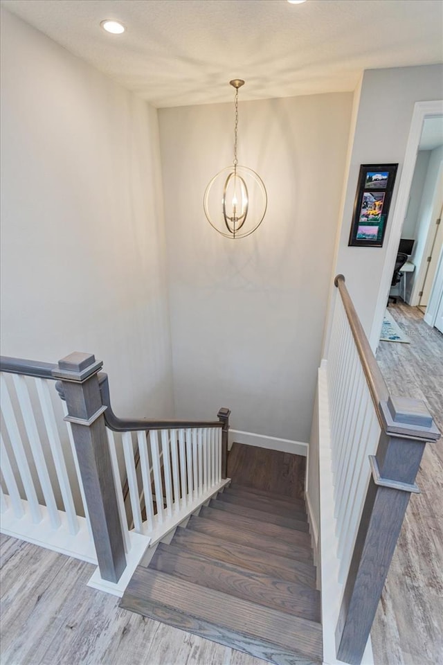 stairway featuring an inviting chandelier and hardwood / wood-style flooring