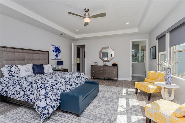 bedroom with ceiling fan, hardwood / wood-style flooring, a raised ceiling, and a textured ceiling