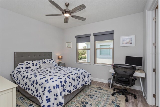 bedroom with ceiling fan, wood-type flooring, and a textured ceiling