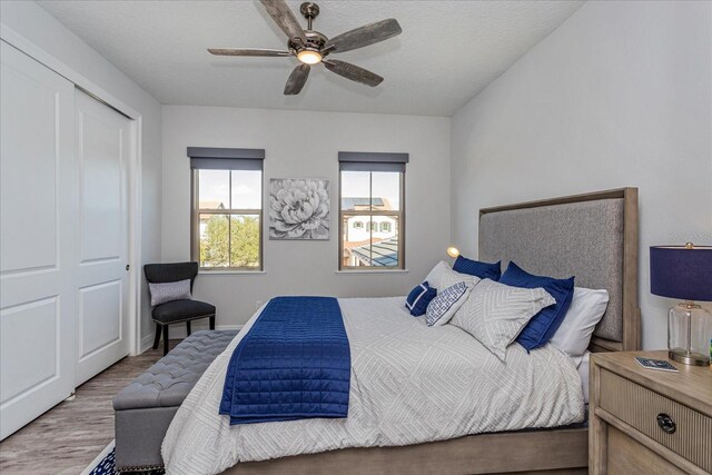 bedroom with hardwood / wood-style flooring, a textured ceiling, ceiling fan, and a closet