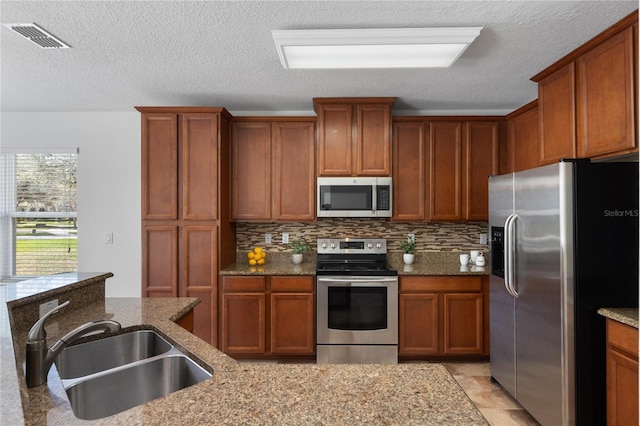 kitchen with light stone counters, sink, and stainless steel appliances