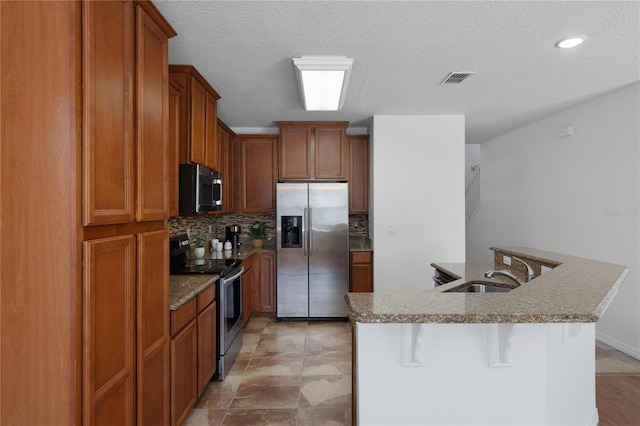 kitchen featuring sink, a breakfast bar, appliances with stainless steel finishes, a kitchen island with sink, and backsplash