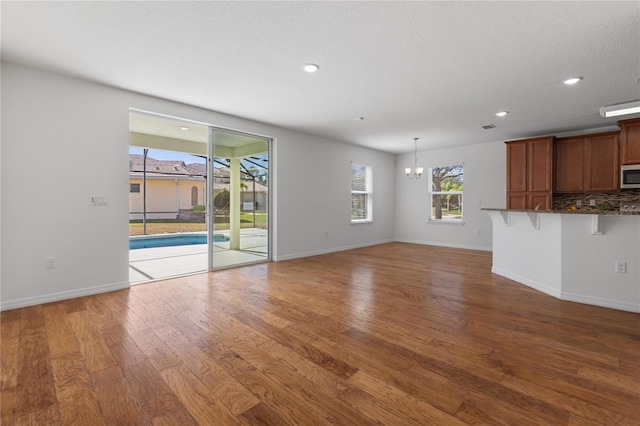 unfurnished living room featuring hardwood / wood-style floors, a notable chandelier, and a textured ceiling