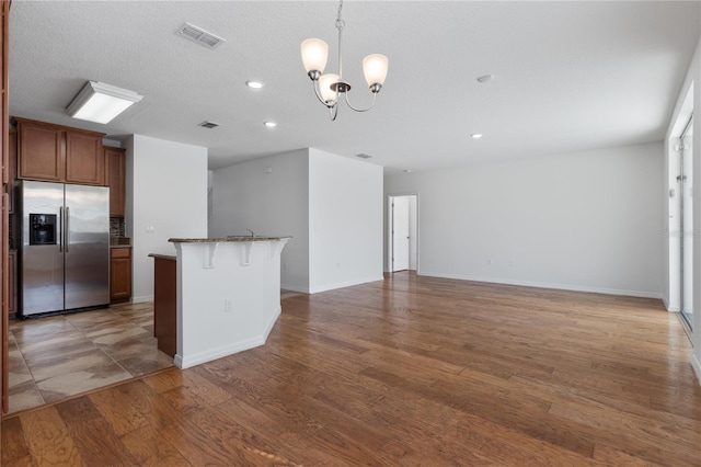 kitchen with a breakfast bar, stainless steel fridge with ice dispenser, hanging light fixtures, dark hardwood / wood-style floors, and a notable chandelier