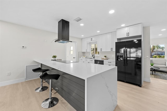 kitchen with light hardwood / wood-style flooring, black appliances, white cabinets, and island exhaust hood