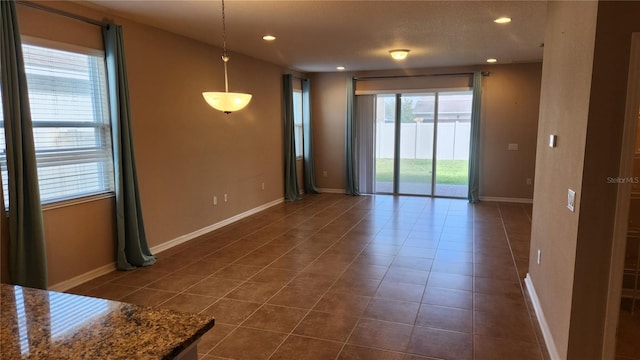 unfurnished room with dark tile patterned floors, recessed lighting, and baseboards