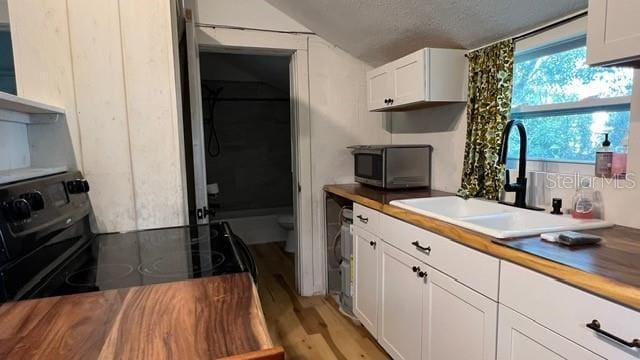 kitchen with white cabinetry, sink, wood counters, and light hardwood / wood-style flooring