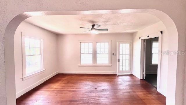 214 N New Hampshire Ave, Tavares, FL 32778 - empty room with ceiling fan, wood finished floors, baseboards, and arched walkways