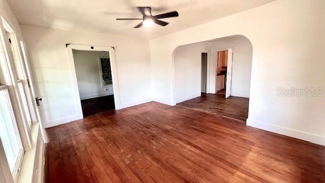 214 N New Hampshire Ave, Tavares, FL 32778 - unfurnished room featuring arched walkways, hardwood / wood-style floors, a ceiling fan, and baseboards