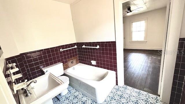 214 N New Hampshire Ave, Tavares, FL 32778 - bathroom with tile walls, a bath, ceiling fan, wainscoting, and a sink