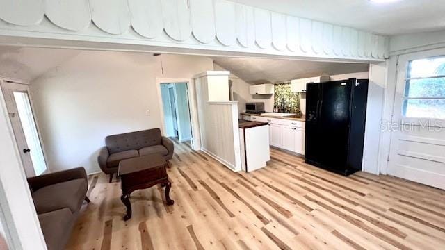 214 N New Hampshire Ave, Tavares, FL 32778 - kitchen with freestanding refrigerator, light wood-style flooring, white cabinets, and vaulted ceiling