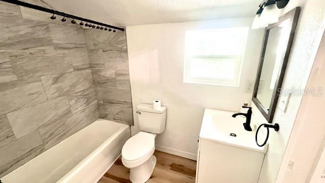 214 N New Hampshire Ave, Tavares, FL 32778 - full bath featuring toilet, vanity, shower / bath combination, baseboards, and wood finished floors