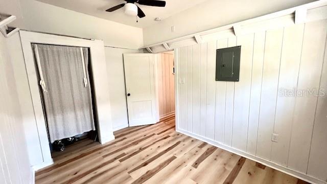 214 N New Hampshire Ave, Tavares, FL 32778 - unfurnished bedroom with electric panel, light wood finished floors, and ceiling fan