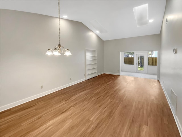 unfurnished living room with hardwood / wood-style flooring, a chandelier, high vaulted ceiling, and built in shelves