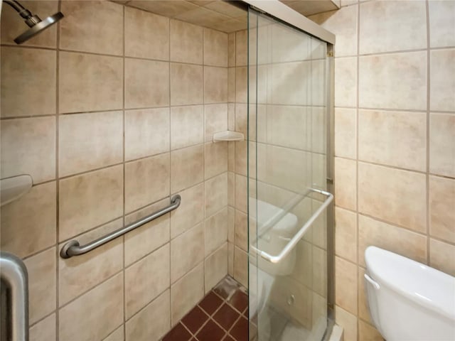 bathroom featuring toilet, an enclosed shower, and tile walls