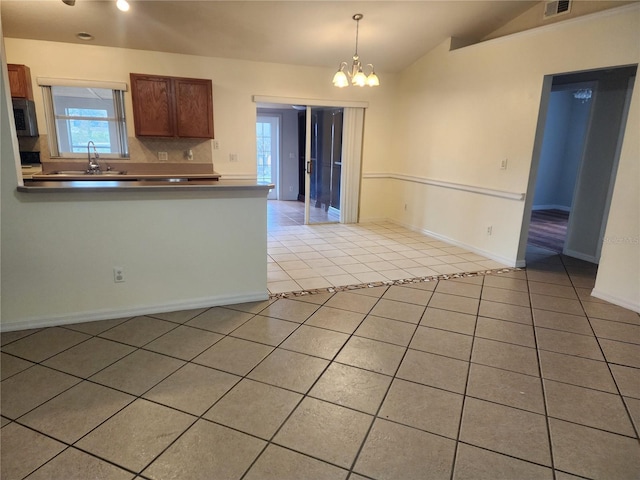 kitchen featuring light tile patterned flooring, decorative light fixtures, lofted ceiling, sink, and a notable chandelier