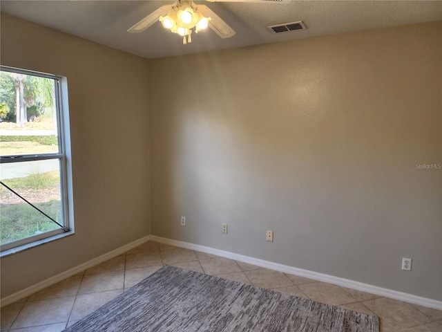 spare room featuring a healthy amount of sunlight, light tile patterned floors, and ceiling fan