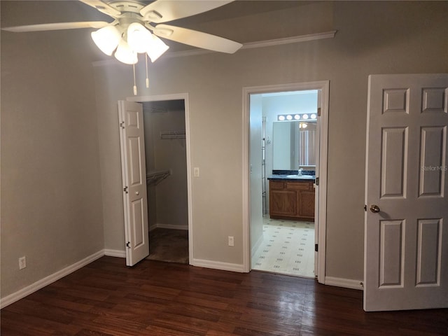 unfurnished bedroom with dark wood-type flooring, sink, ensuite bath, a spacious closet, and a closet