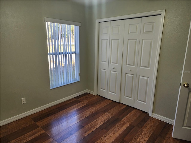 unfurnished bedroom featuring dark wood-type flooring and a closet