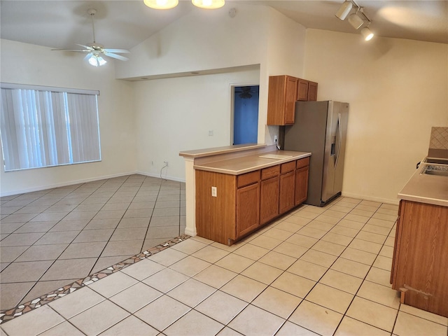 kitchen featuring lofted ceiling, kitchen peninsula, stainless steel fridge with ice dispenser, and light tile patterned floors