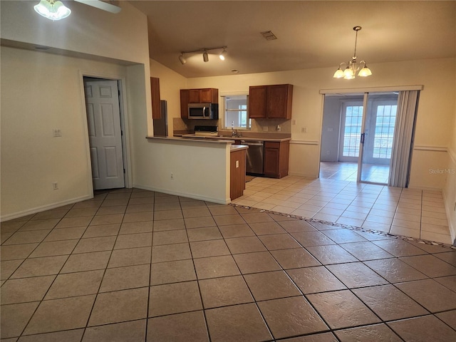 kitchen with light tile patterned flooring, sink, hanging light fixtures, appliances with stainless steel finishes, and kitchen peninsula