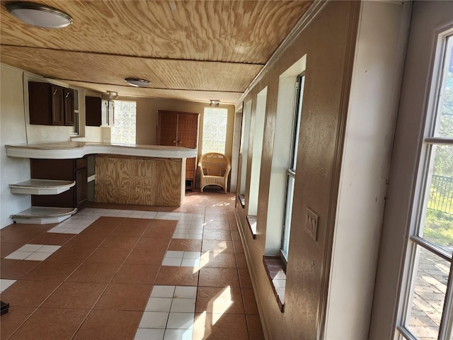 kitchen with light tile patterned floors, wood ceiling, and kitchen peninsula