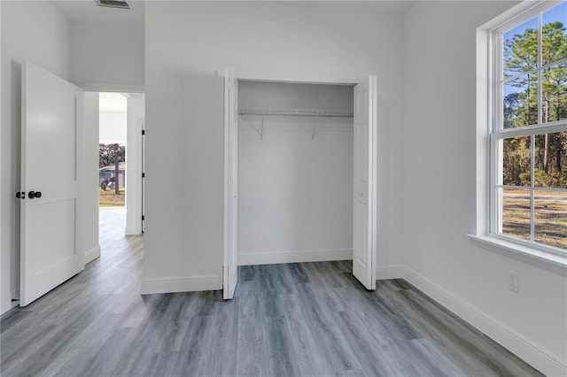 unfurnished bedroom with multiple windows, light wood-type flooring, and a closet