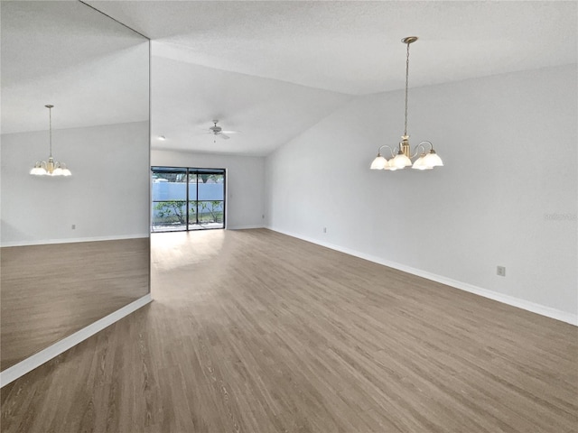 empty room with dark hardwood / wood-style flooring, ceiling fan with notable chandelier, and lofted ceiling