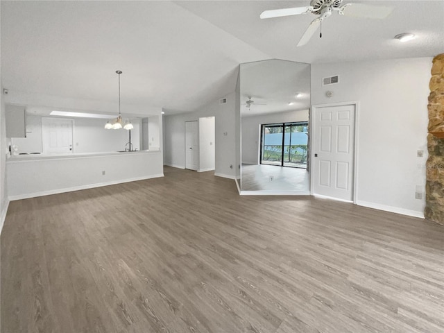 unfurnished living room featuring hardwood / wood-style flooring, vaulted ceiling, and ceiling fan with notable chandelier