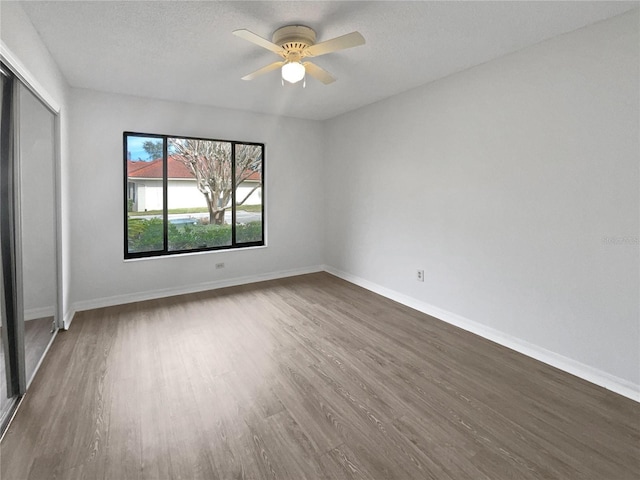 unfurnished bedroom featuring ceiling fan, dark wood-type flooring, a textured ceiling, and a closet