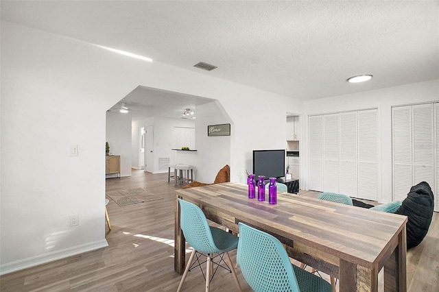 dining area featuring wood-type flooring and a textured ceiling