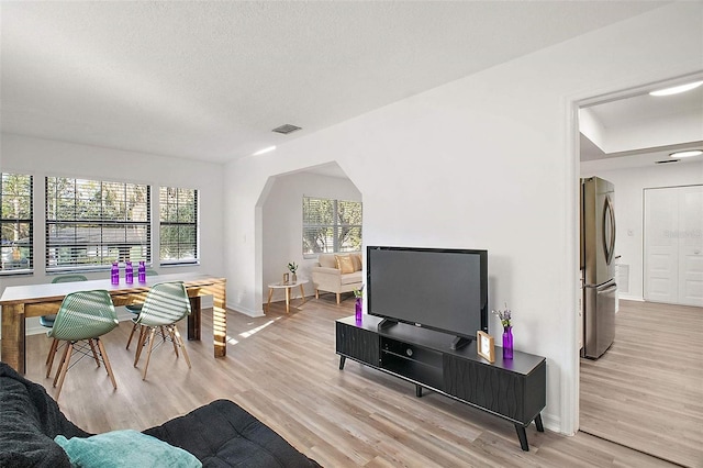 living room with a textured ceiling and light wood-type flooring