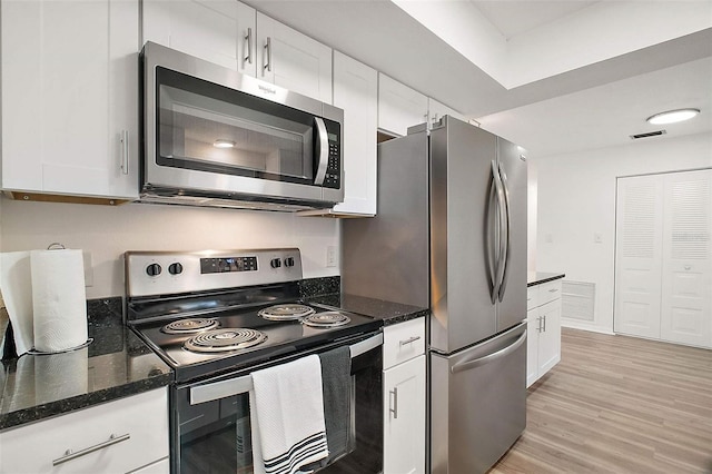 kitchen with white cabinetry, appliances with stainless steel finishes, and dark stone counters