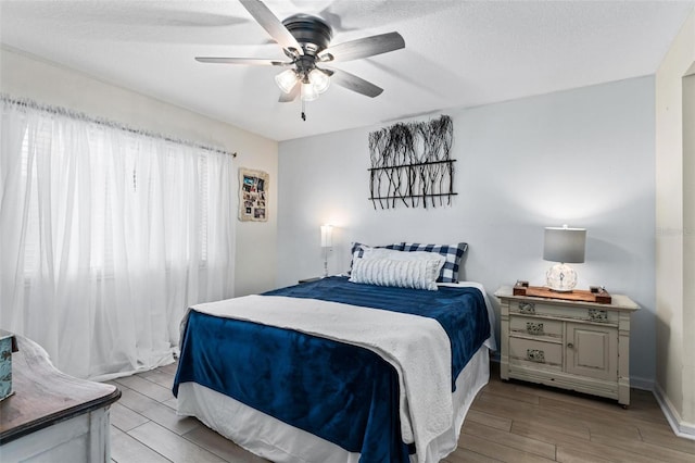 bedroom featuring ceiling fan, a textured ceiling, and light hardwood / wood-style floors