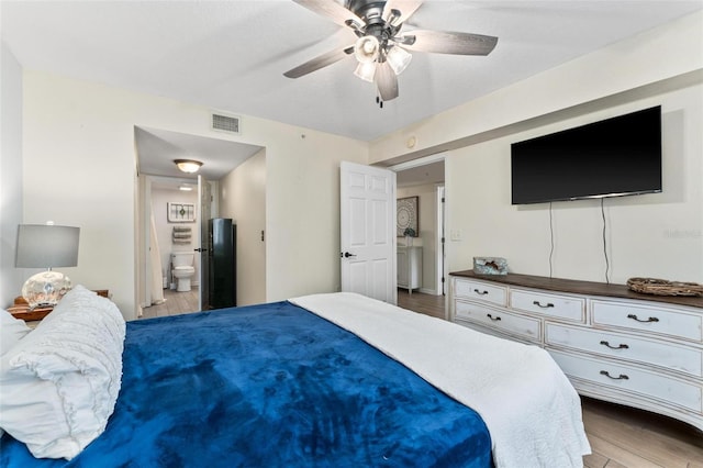 bedroom with ceiling fan, ensuite bath, and light hardwood / wood-style flooring