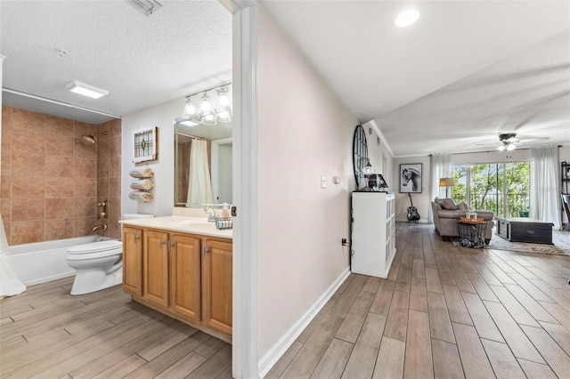 full bathroom with shower / bathtub combination with curtain, ceiling fan, vanity, a textured ceiling, and toilet