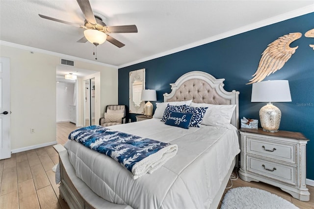 bedroom featuring ornamental molding, ensuite bathroom, ceiling fan, and light wood-type flooring