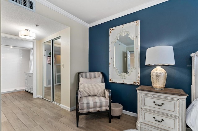 sitting room with crown molding and light hardwood / wood-style floors