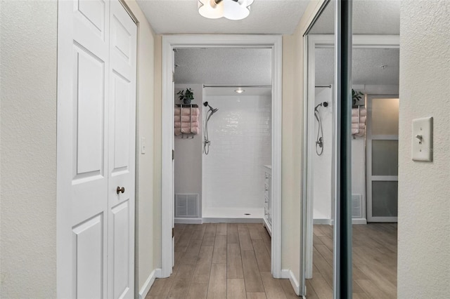 hallway featuring light hardwood / wood-style flooring and a textured ceiling