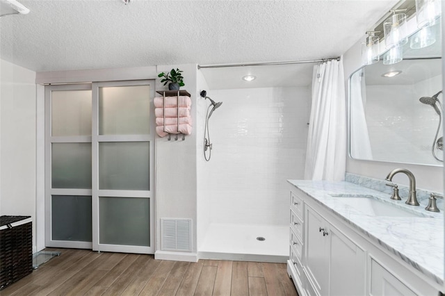 bathroom featuring wood-type flooring, vanity, a textured ceiling, and a shower with curtain