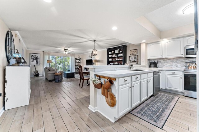 kitchen with sink, decorative light fixtures, white cabinets, and appliances with stainless steel finishes