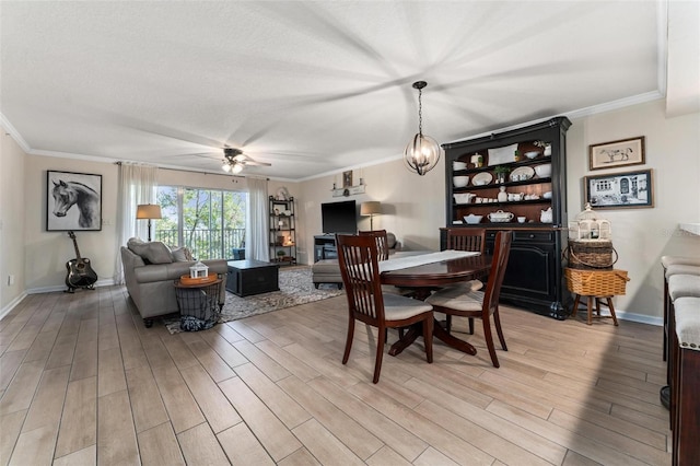 dining space with crown molding, ceiling fan with notable chandelier, a textured ceiling, and light wood-type flooring